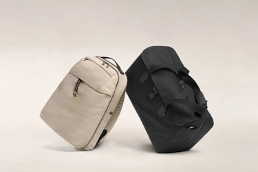 A black Away duffle next to a sand Away backpack.