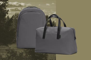 An asphalt Away daypack next to an asphalt Away everywhere bag on a forest inspired background.