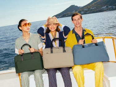 Three travelers carrying three sizes of The Everywhere Bag