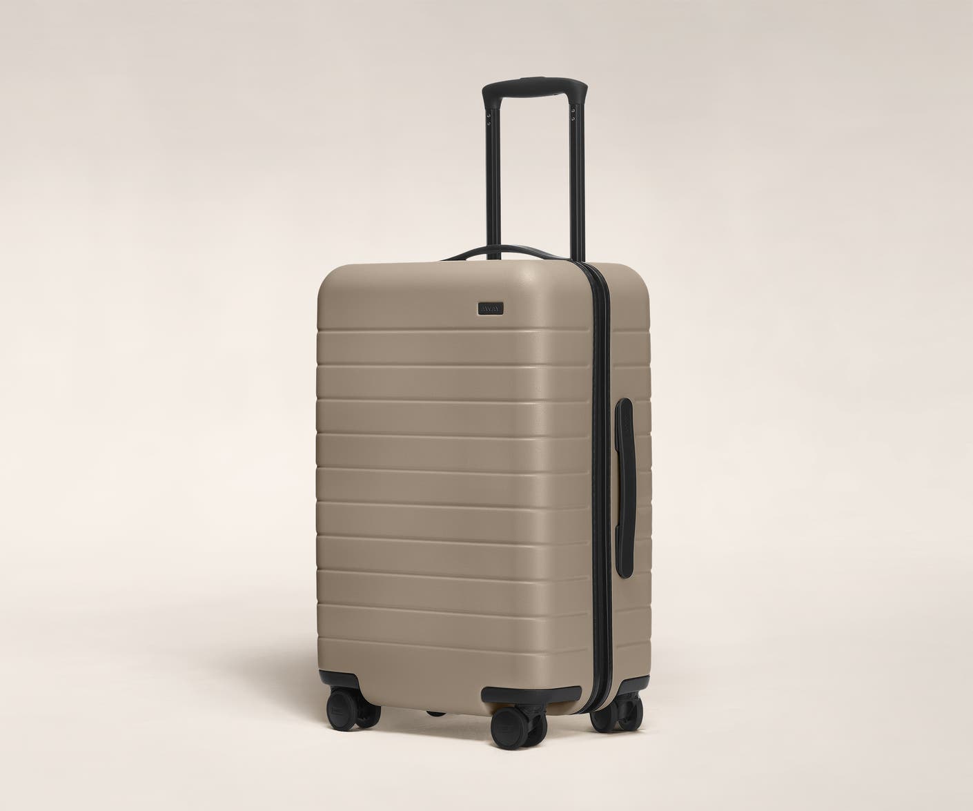 The Bigger Carry-On in Sand shown at an angle with raised telescoping handle