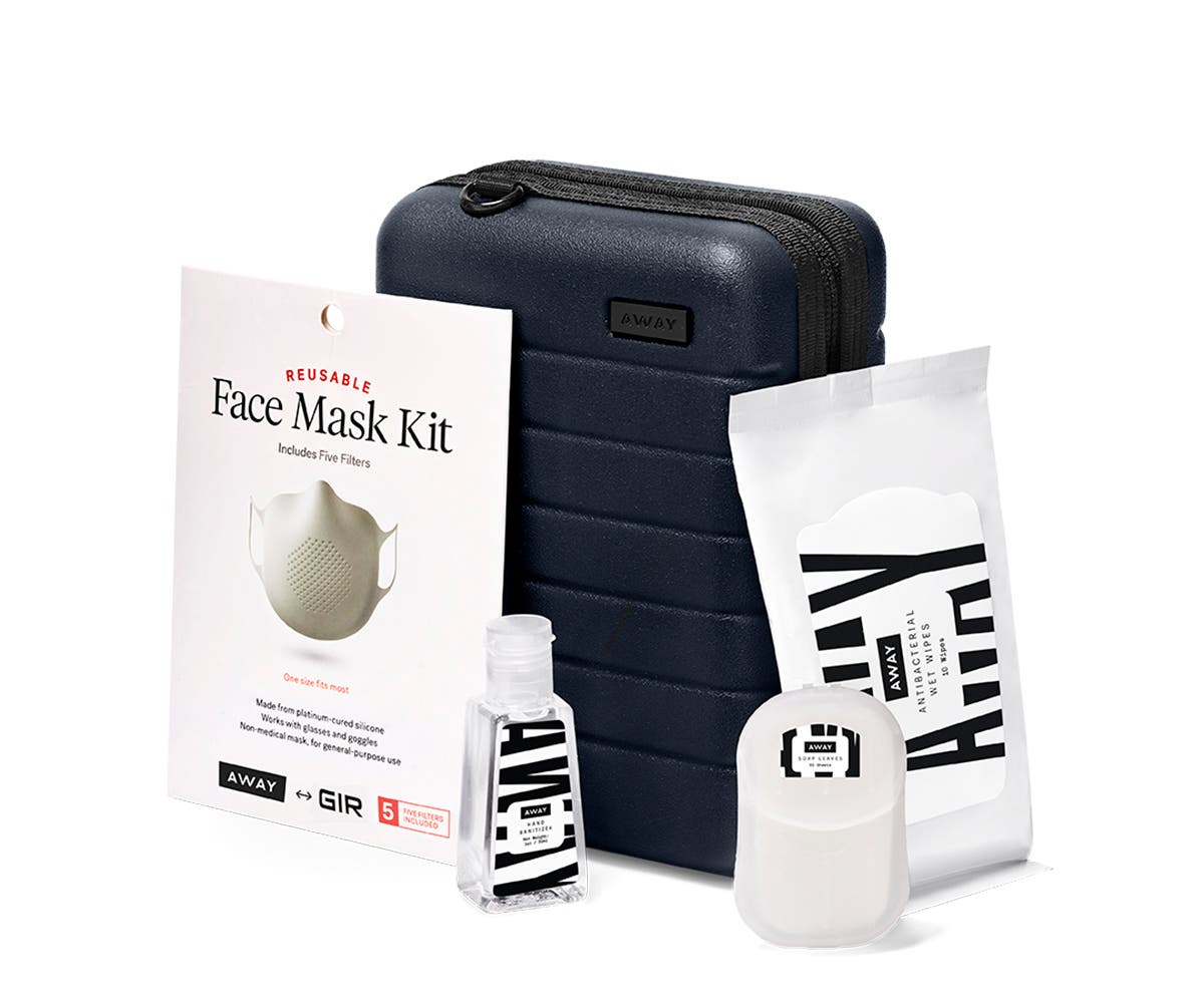 Mini suitcase in navy shown behind a bottle of hand sanitizer, wipes, soap sheets and mask.