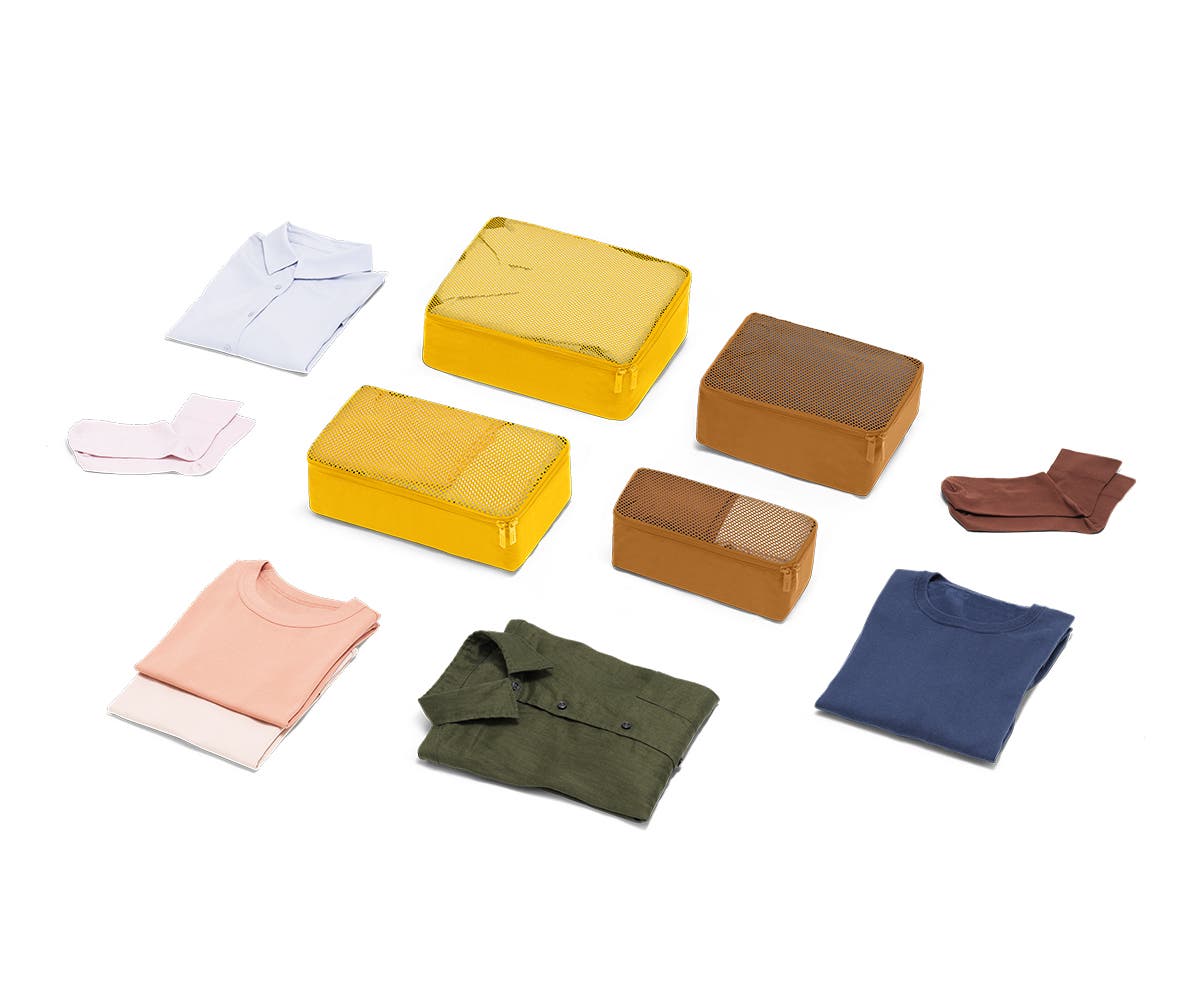 Set of four packing cubes in Golden with clothes displayed around it