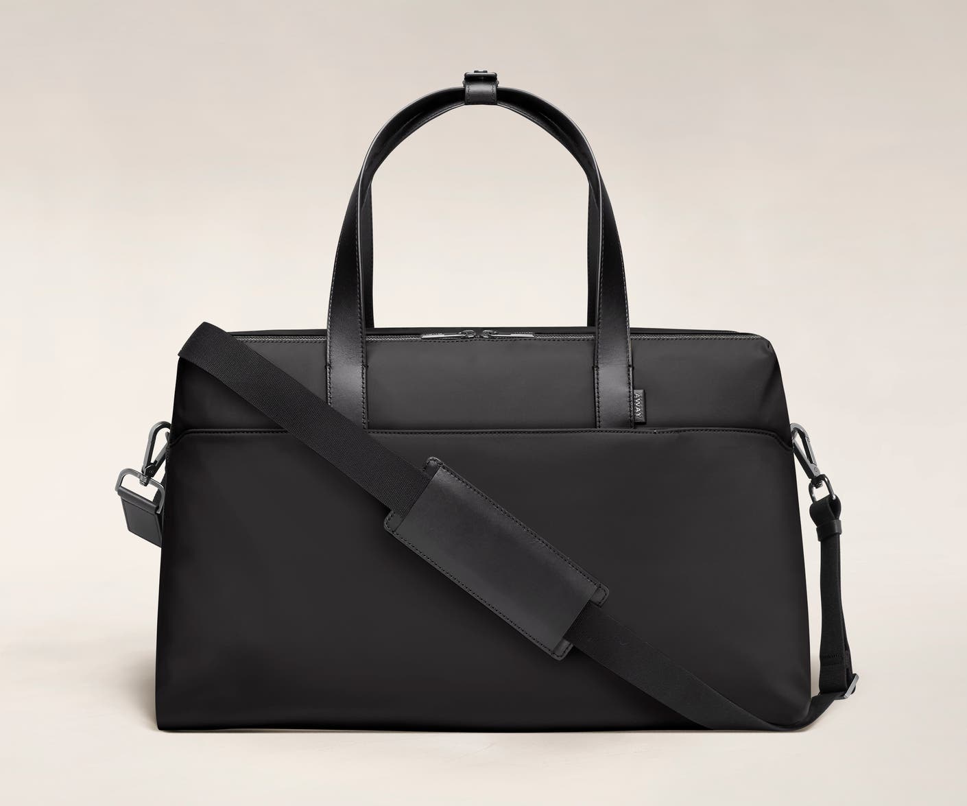 Large shoulder bag in black with raised handles and shoulder strap across the bag.