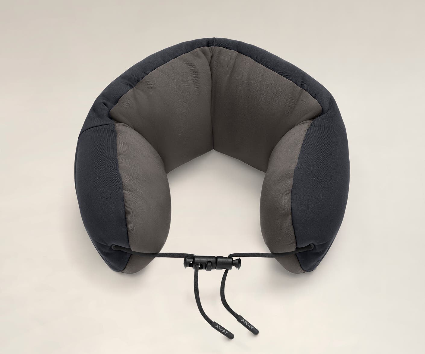Aerial angled view of a navy and grey travel neck pillow with a string loop on one side.