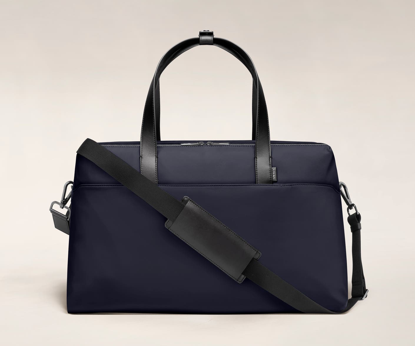 Large duffle bag in navy with back zip pocket, and shoulder strap across the bag.