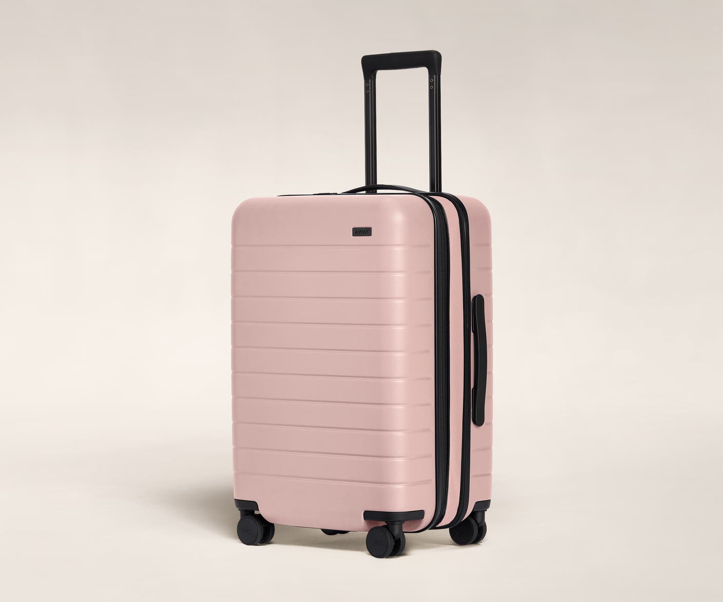 The Bigger Carry-On Flex in Petal shown at an angle with raised telescoping handle.