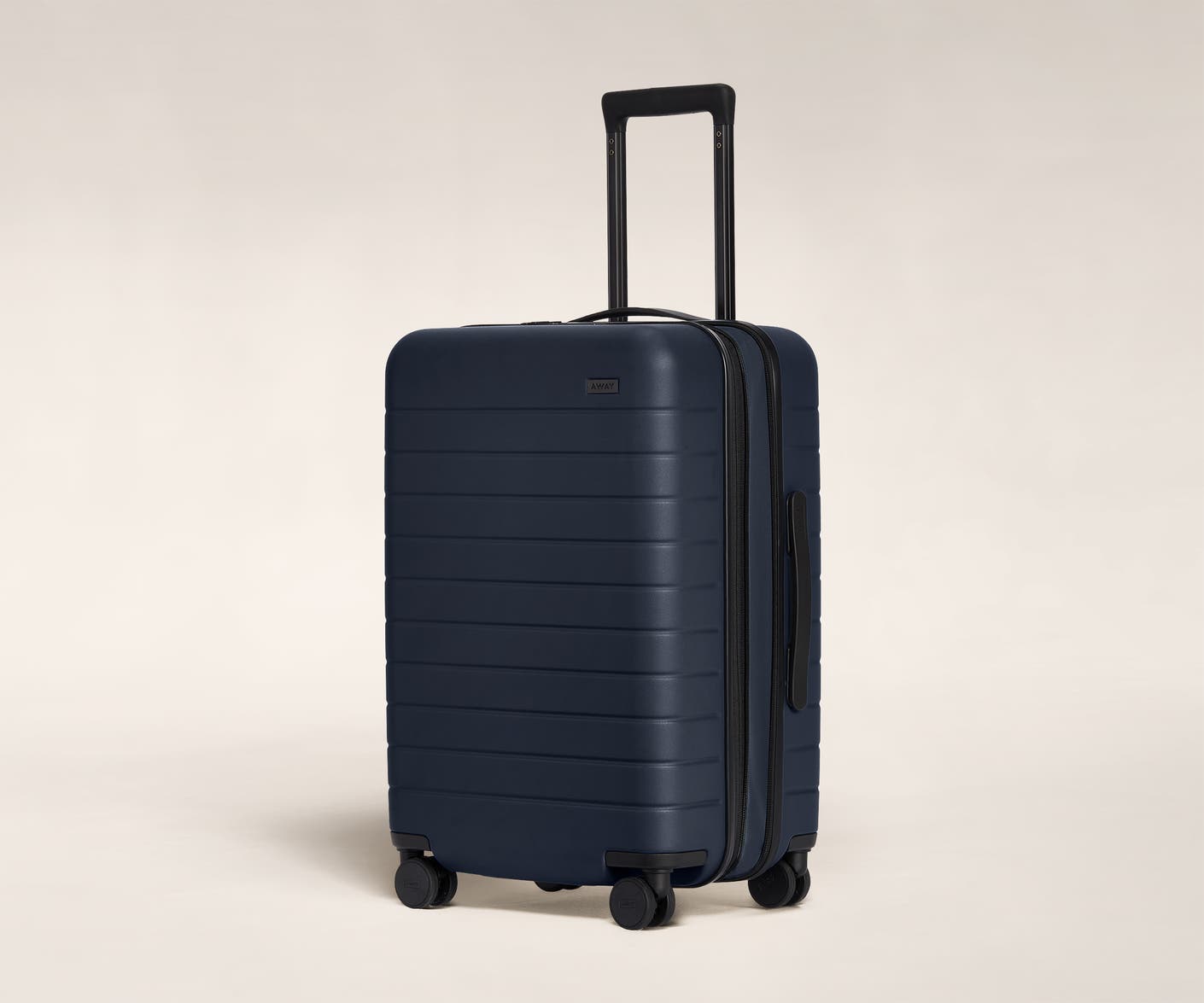 The Bigger Carry-On Flex in Navy shown at an angle with raised telescoping handle.