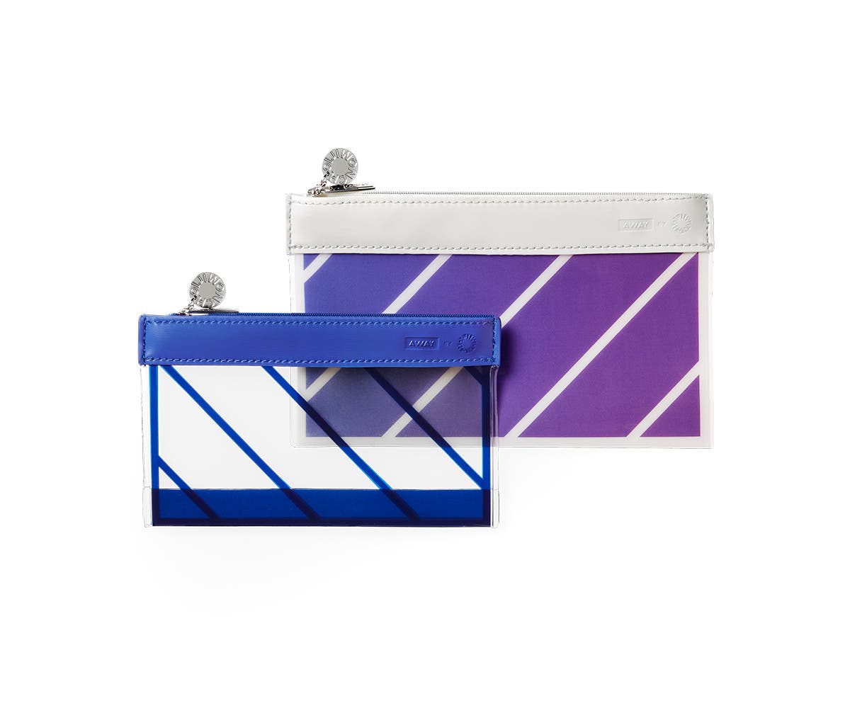 The Travel Pouch Set by Ji Won Choi in a smaller and larger size. One opaque with blue stripes, and one an ombre purple and blue with white stripes