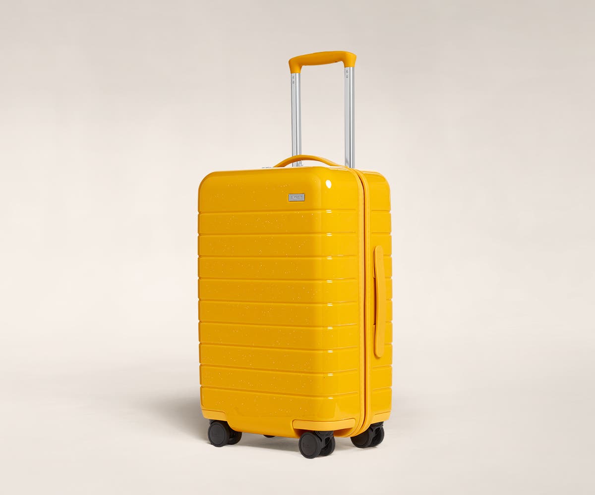 A saffron sparkle Carry-On with raised telescopic handles shown at an angle.