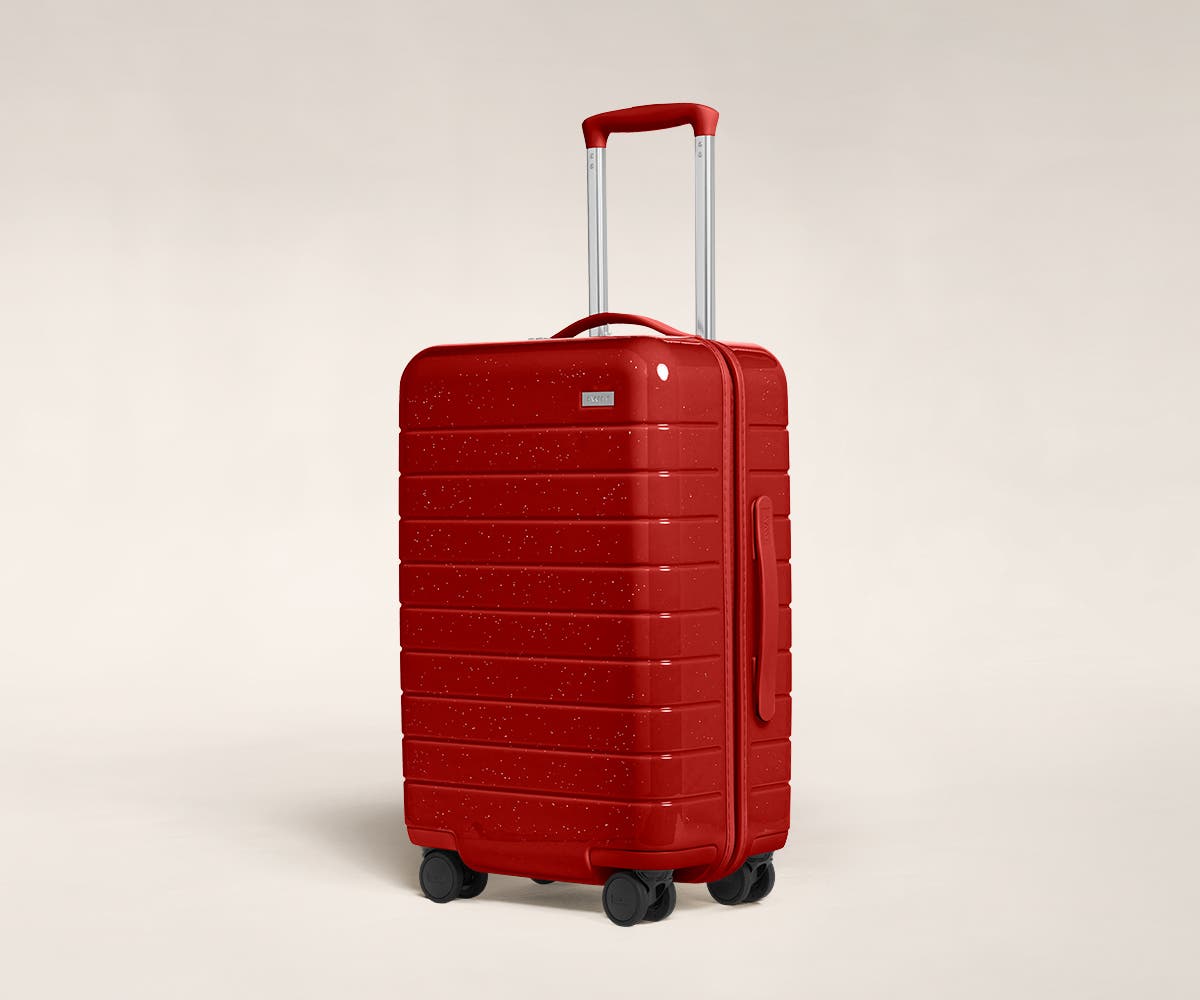 A cranberry sparkle Carry-On with raised telescopic handles shown at an angle.