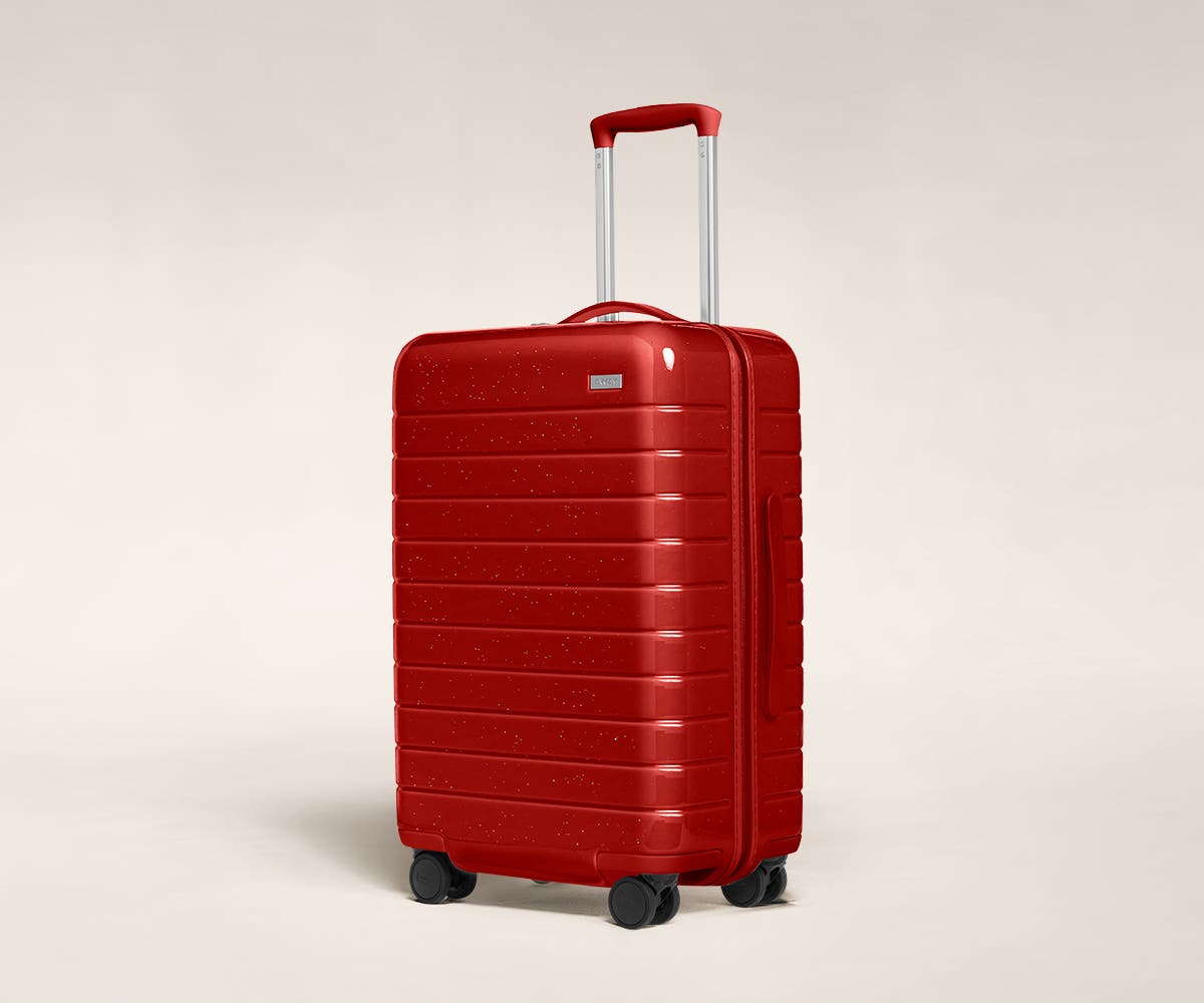 A cranberry sparkle Bigger Carry-On with raised telescopic handles shown at an angle.
