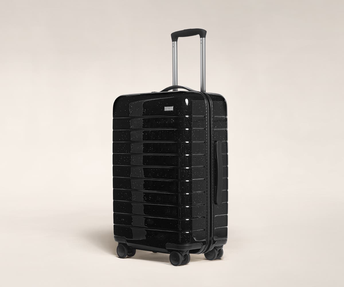 A black sparkle Bigger Carry-On with raised telescopic handles shown at an angle.