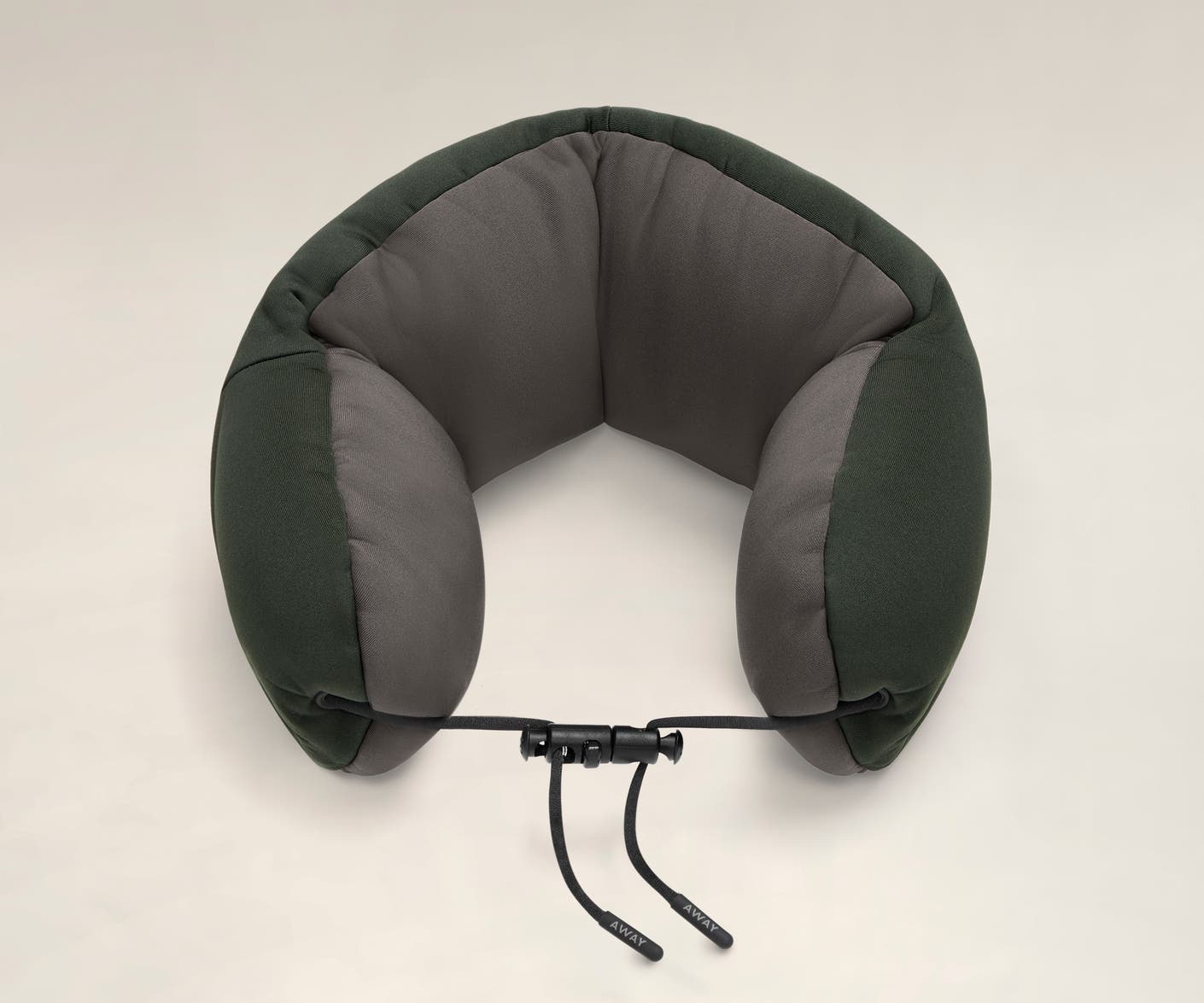 Aerial angled view of a green and grey travel neck pillow with a string loop on one side.