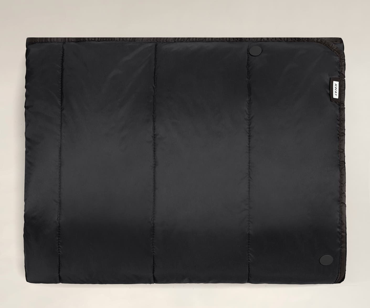 A black Away travel blanket laid flat front side up.