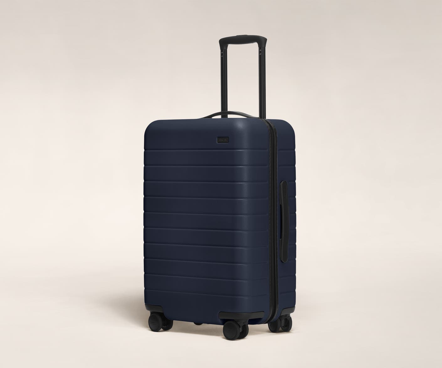 The Bigger Carry-On in Navy shown at an angle with raised telescoping handle