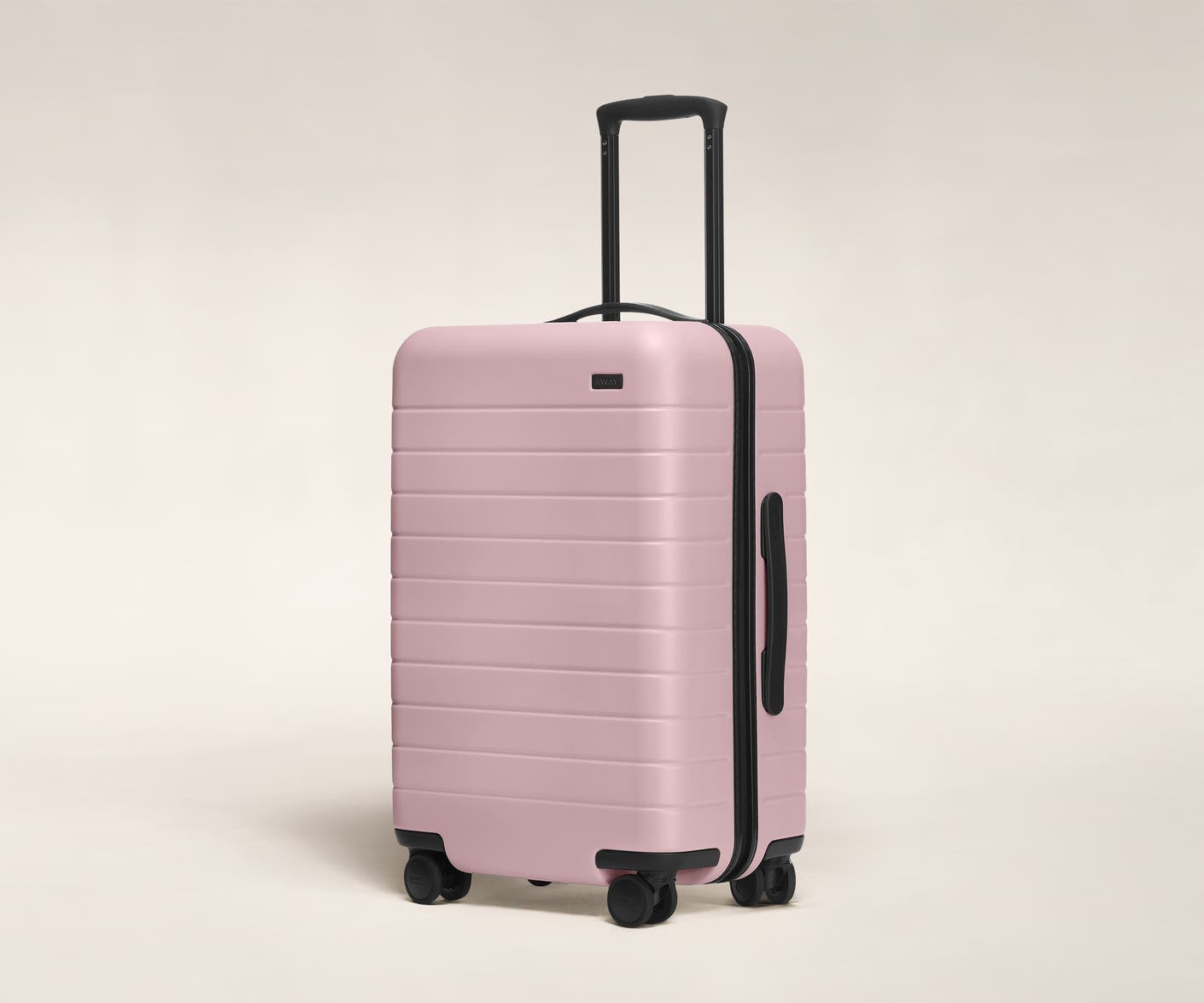 The Bigger Carry-On in Blush shown at an angle with raised telescoping handle