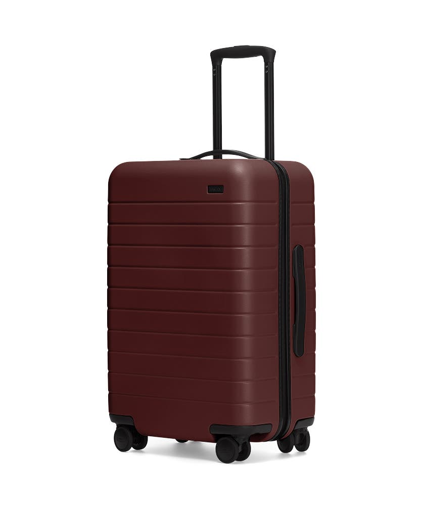 The Bigger Carry-On in Brick shown at an angle with raised telescoping handle