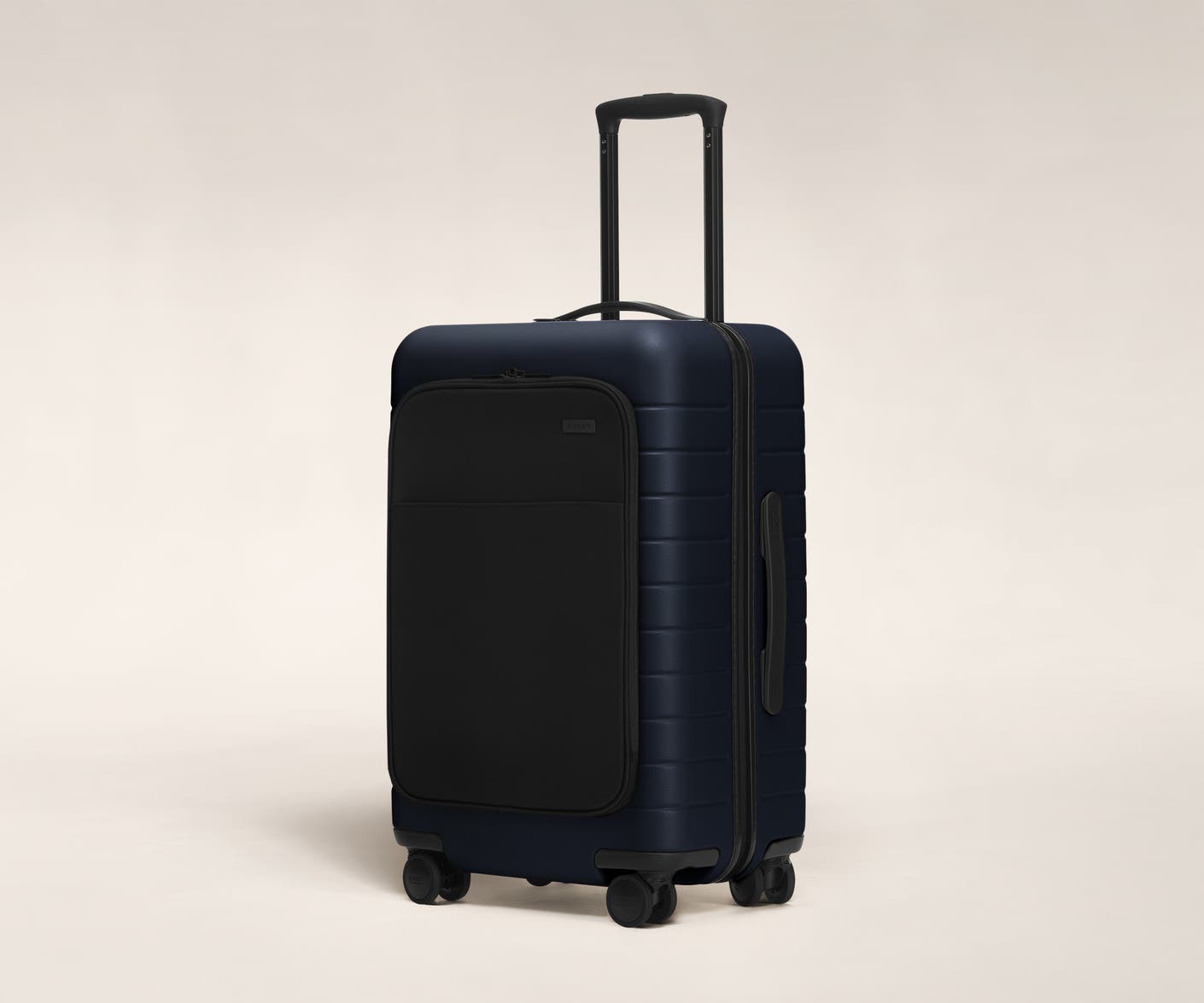 The Bigger Carry-On with Pocket in Navy shown at an angle with raised telescoping handle